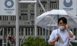 Un homme marche prĂšs du siĂšge du gouvernement mĂ©tropolitain de Tokyo oĂč l'on aperçoit des affiches des JO-2020. Photo prise le 13 juillet 2020.