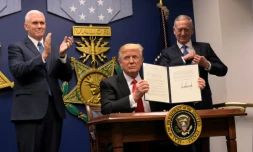 Le président américain Donald Trump signe un décret lors de la cérémonie d'investiture du secrétaire américain à la Défense James Mattis (d) en présence du vice-président Mike Pence (g), le 27 janvier 2017 au Pentagone, à Washington