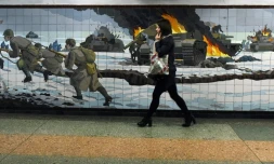 Une femme passe devant une mosaïque murale représentant une scène de bataille de la Deuxième guerre mondiale dans la ville russe de Rostov-sur-le-Don frontalière de l'Ukraine le 22 février 2022.