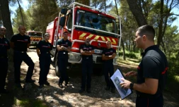 Des pompiers Ă©coutent les instructions dans une forĂȘt de Gardanne, le 25 juillet 2023 dans les Bouches-du-RhĂŽne