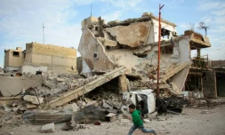 Un garçon syrien court devant un immeuble détruit par des raids du régime dans la ville de Douma, dans le fief rebelle de la Ghouta orientale, le 20 février 2018