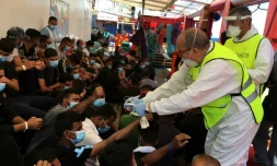 Un médecin italien distribue des bracelets numérotés à des migrans secourus sur le navire humanitaire Ocean Viking, le 5 juillet 2020 en Méditerranée