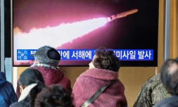 Des gens regardent un journal télévisé diffusant des images d'archives d'un essai de missile nord-coréen, dans une gare de Séoul, le 30 janvier 2024