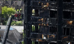 Des pompiers sur une grande échelle inspectent les décombres de la tour Grenfell à Londres le 16 juin 2017