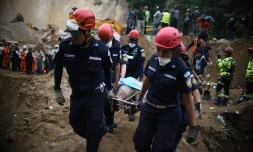 Des pompiers transportent un corps après un glissement de terrin près de Guatemala city le 3 octobre 2015