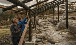 Athanassia Pistola (d) aide son mari Thanassis à clouer le toit d'une structure provisoire pour leur bergerie après un incendie dans une forêt de la région d'Evros, près du village de Dadia, le 26 octobre 2023 en Grèce