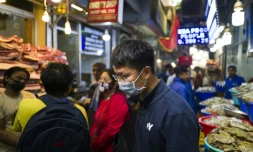 Des personnes portant un masque de protection font leurs courses dans un marché de viande et de poisson, le 14 mars 2020 à New Delhi, en Inde