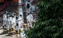 Des policiers de l'unité d'identification des victimes de catastrophes, vêtus d'une combinaison de protection, examinent le complexe résidentiel de Wang Fuk Court après l'incendie qui l'a ravagé, à Hong Kong le 29 novembre 2025