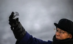 Kiyoshi Miyasaka, prêtre japonais du culte shinto, brandit un morceau de glace du lac Suwa, le 29 janvier 2026 dans la préfecture de Nagano, dans le centre de l'archipel 