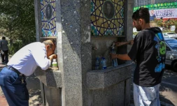 Des passants boivent de l'eau à une fontaine publique dans une rue de Téhéran pendant une vague de chaleur en Iran, le 22 juillet 2025