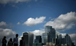 Des passants le long de la rive sud de la Tamise d'où l'on aperçoit le quartier des affaires et financier du centre de Londres, le 14 août 2025
