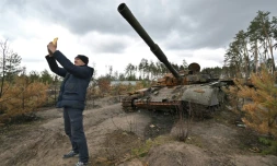 Un homme fait un selfie devant un tank russe détruit dans le village d'Andriivka, dans la région de Kiev, le 17 avril 2022