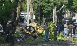 Des membres de la police colombienne inspectent la zone d'une explosion au camion piégé à Cali, en Colombie, le 21 août 2025