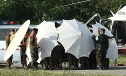 Des policiers et des militaires recouvrent une civière avec des parapluies le 9 juillet 2018 alors que se poursuivent les opérations de sauvetage pour de jeunes footballeurs coincés dans une grotte en Thaïlande 