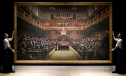 Deux assistants manipulent la toile de Banksy "Devolved Parliament" (Parlement dévolu), le 27 septembre 2019 à Londres