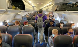 Des passagers d'un vol d'American Airlines Ă destination de Charlotte portent un masque de proection, Ă l'exception d'un seul, le 3 mai 2020 Ă New York