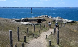 Des visiteurs regardent les ruines d'un bunker allemand avec un canon rouillé, le 5 août 2022 sur l'île de Cézembre, au large de Saint-Malo