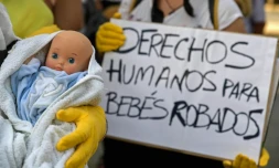 Des manifestants arborent un poupon et une pancarte réclamant des "droits" pour "les bébés volés" sous la dictature de Franco, à Madrid le 26 juin 2018