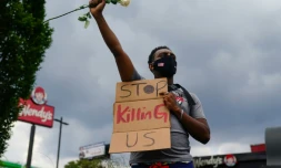 Un manifestant tient une pancarte implorant "arrĂȘtez de nous tuer", devant le restaurant prĂšs duquel est mort l'avant-veille Rayshard Brooks, un Afro-AmĂ©ricain tuĂ© par un policier blanc, Ă Atlanta le 14 juin 2020