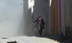 De la fumĂ©e envahit une rue de Kaboul oĂč un Afghan court se mettre Ă l'abri aprĂšs un attentat contre un centre culturel chiite, le 28 dĂ©cembre 2017