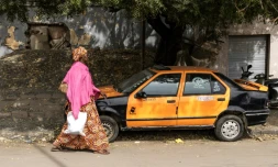 Une femme passe devant un taxi à Dakar, le 13 février 2024