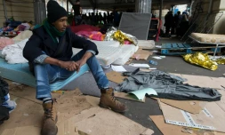 Un migrant assis sur un matelas dans un camp sous la station de métro Stalingrad à Paris le 24 mars 2016