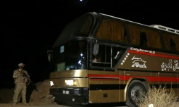 Un membre des forces de sécurité syriennes escorte un bus transportant des membres du groupe Etat islamique et leurs familles, à Qalamoun, en Syrie, le 28 août 2017