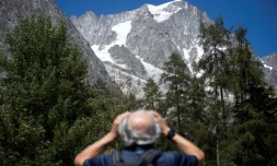 Un homme observe avec des jumelles le glacier de Planpincieux à Courmayeur, le 6 août 2020 au Val Ferret, en Italie