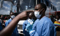 Un membre du Centre biomédical du Rwanda prend la température des passagers à un gare routière à Kigali, le 22 mars 2020