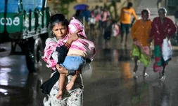 Une femme, un enfant dans les bras, se dirige vers un abri Ă l'approche du cyclone Arnab, le 27 octobre 2026 Ă Kakinada, dans l'Etat de l'Andhra Pradesh, en Inde