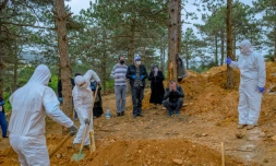 Des personnels funéraires en combinaison de protection enterrent une personne décédée du coronavirus en présence de la famille, le 21 mai 2020 à Istanbul, en Turquie