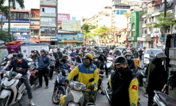Des motocyclistes font la queue pour faire le plein d'essence dans une station-service à Hanoï, le 10 mars 2026 au Vietnam