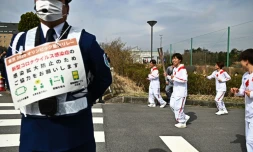 La footballeuse internationale japonaise Azusa Iwashimizu porte la torche habritant la flamme olympique à Naraha dans le département de Fukushima le 25 mars 2021.