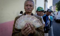 Un homme montre ses billets de 100 bolivars en attendant de pouvoir les échanger à la banque centrale du Venezuela à Caracas, le 16 décembre 2016