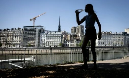 Une jeune femme s'hydrate pendant la canicule, le 24 juin 2026 Ă Paris