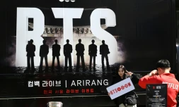 Une femme pose pour une photo devant un camion faisant la promotion du concert de retour du boys band de K-pop BTS à Séoul, le 19 mars 2026