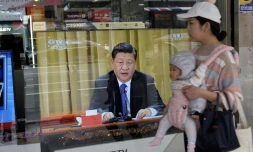 Une femme passe avec son bébé à Nouveau Taipei le 2 janvier 2019 devant une télévision montrant le président chinois Xi Jinping qui prononce un discours intransigeant envers Taïwan
