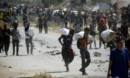 Des Palestiniens transportent des sacs d'aide humanitaire, dans le camp de Nousseirat, dans le centre de la bande de Gaza, le 27 juillet 2025