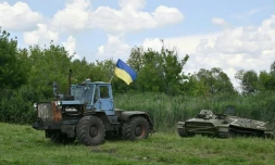 Un fermier ukrainien remorque un blindé de transport de troupes russe abandonné près du village de Mala Rogan, dans la région de Kharkiv, le 28 juillet 2022
