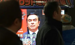 Des piétons passent devant un écran de télévision sur lequel apparaît le visage de Carlos Ghosn, ex-PDG de Nissan, le 21 décembre 2018 à Tokyo, au Japon