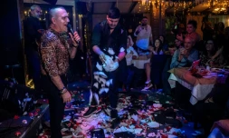 Un chanteur se produit sur la scÚne d'une taverne pendant qu'un employé brise des assiettes, le 7 janvier 2024 dans la banlieue d'AthÚnes