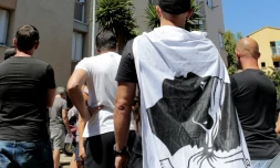 Un homme arbore un drapeau corse pendant une manifestation à la cité des Monts à Lupino, le 14 août 2016, après une rixe sur une plage à Sisco