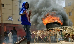 Un manifestant soudanais fait le "V" de la victoire devant un pneu en flammes, le 3 juin 2019 près du siège de l'armée à Khartoum