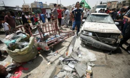 Des passants constatent les dégùts aprÚs l'explosion d'une voiture piégée prÚs d'un marché du grand quartier chiite Sadr City, dans le nord de Bagdad le 11 mai 2016
