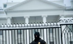 Un membre des services secrets américains devant la Maison Blanche enneigée le dimanche 13 janvier 2019 à Washington