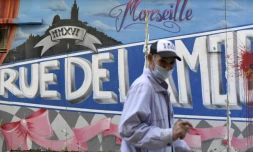Un homme portant un masque devant un graffiti à Marseille, France, le 14 septembre 2020