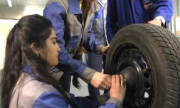En bleu de travail, Marjona Abdoulloeva examine attentivement le châssis d'une Opel garée devant un centre de formation géré par l'Etat au Tadjikistan