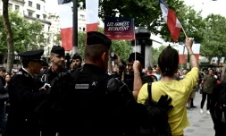 Des gendarmes entourent une jeune femme habillée en jaune criants des slogans anti-Macron, lors du défilé du 14 juillet 2019 sur les Champs-Elysées à Paris