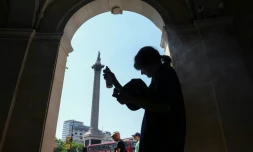 Une femme se protÚge de la chaleur du soleil, dans l'ombre d'une entrée sur Trafalgar Square, à Londres, le 8 juillet 2026