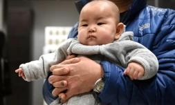 Un bébé chinois dans les bras de son père le 19 janvier 2015 à Pékin
